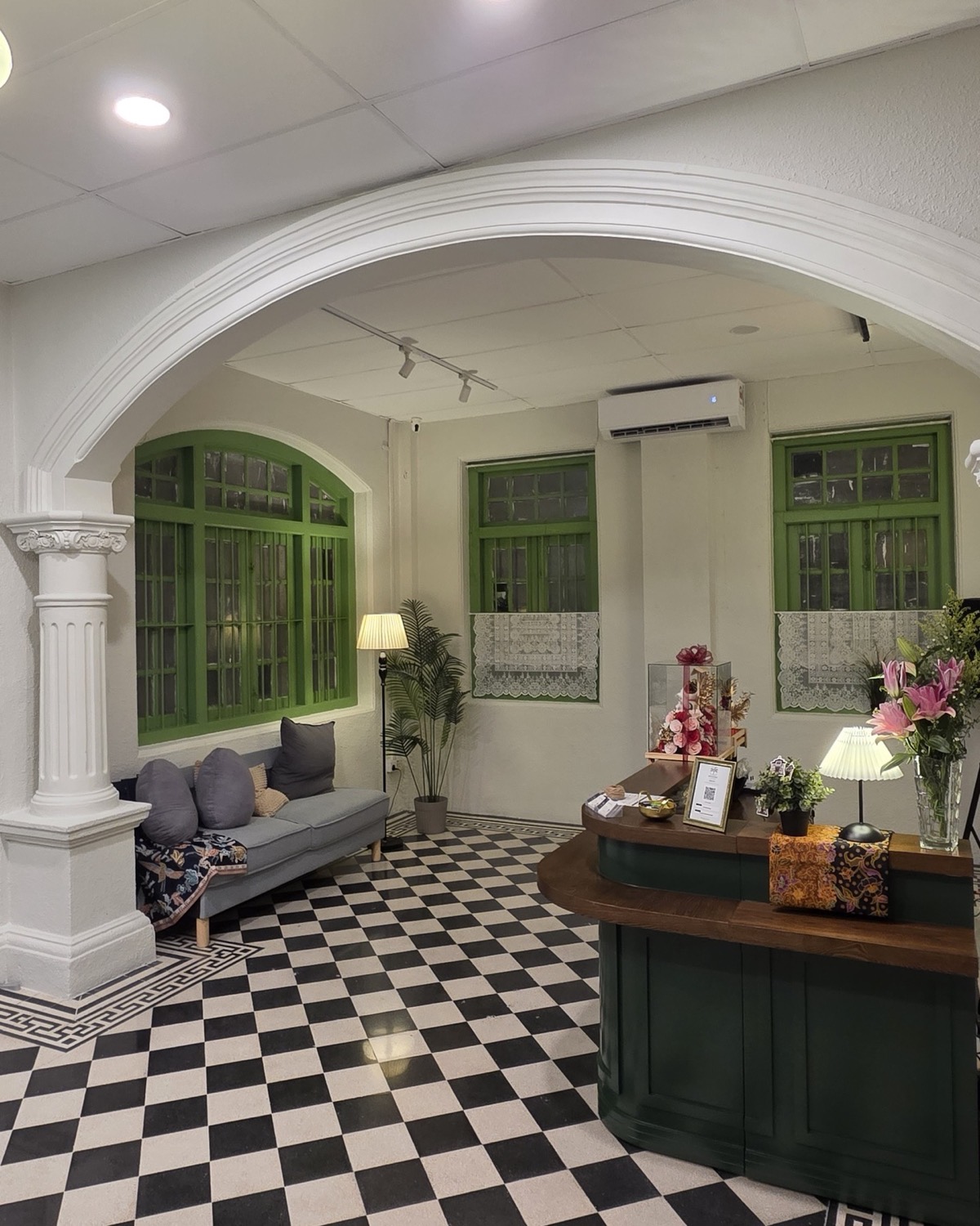 Reception seating beneath a heritage arch with original green timber windows